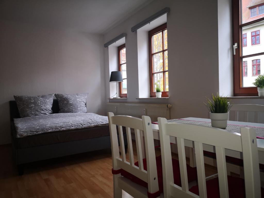 um quarto com uma mesa, uma cama e janelas em Daheym FEWO 1 em Erfurt