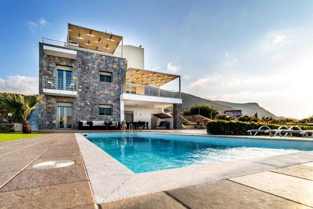 uma casa com uma piscina em frente em Aroma Villas em Hersonissos