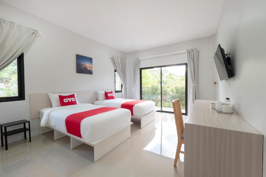 羅勇的住宿－Capital O 75378 Thawapee Resort，一间卧室配有两张床、一台电视和一张桌子