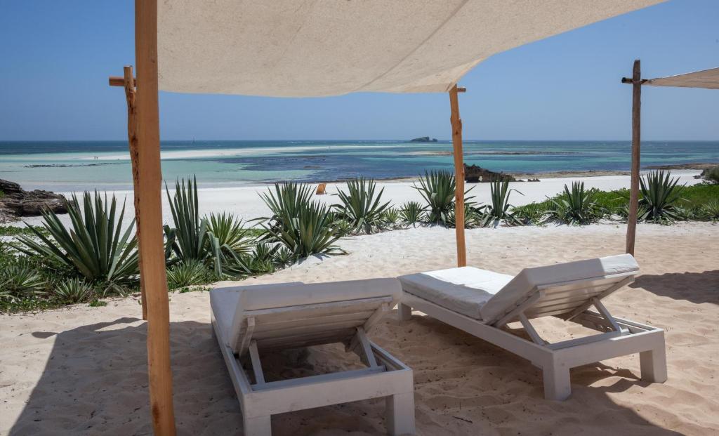 a white chair under an umbrella on the beach at Gecko Resort in Watamu