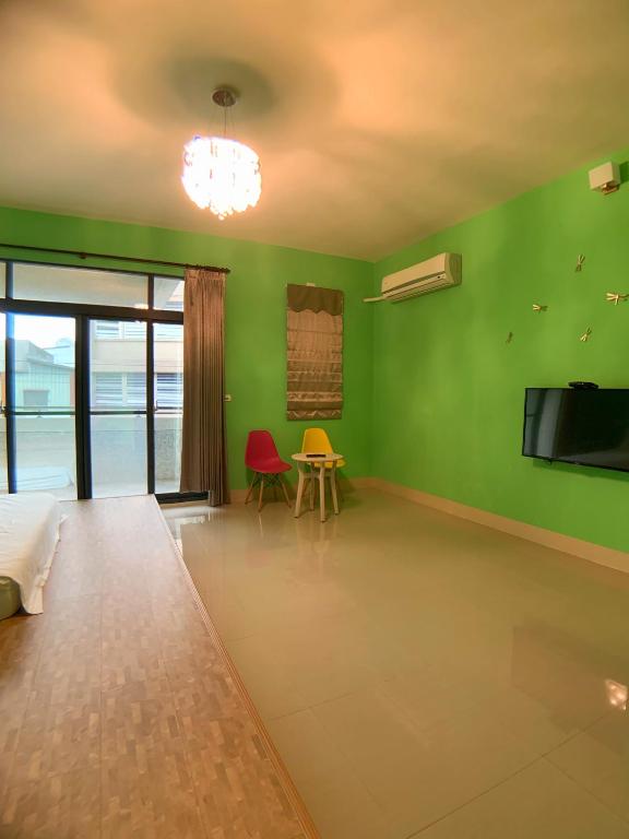 a green room with a bed and a table and a tv at EZE Homestay in Ji&#39;an