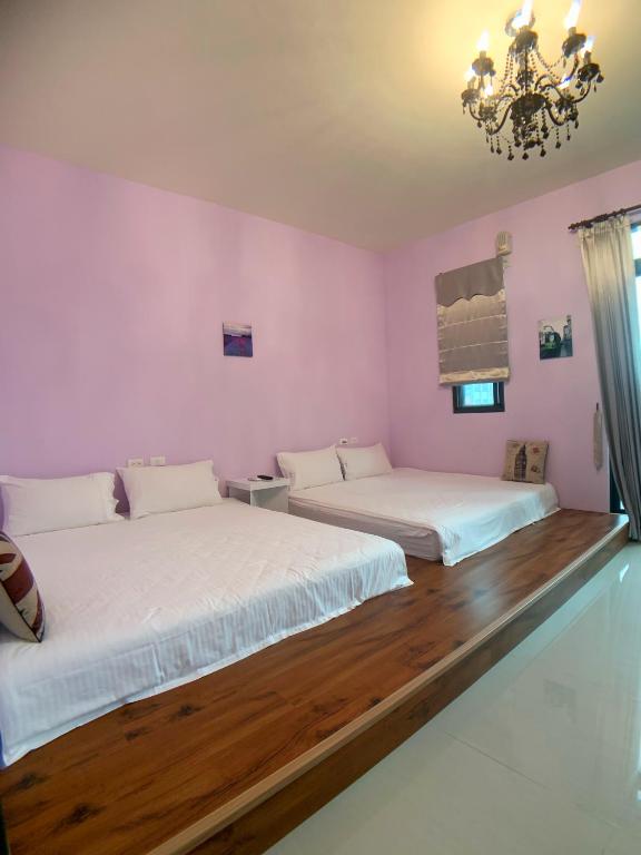 two beds in a room with pink walls and wooden floors at EZE Homestay in Ji&#39;an