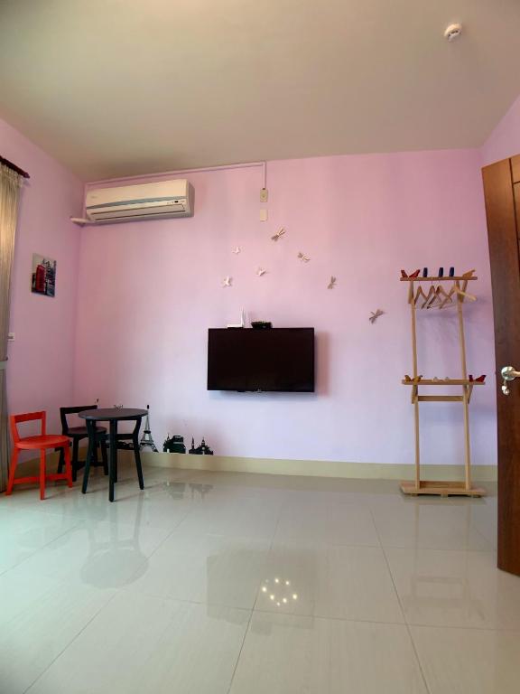 a living room with a tv on a pink wall at EZE Homestay in Ji&#39;an