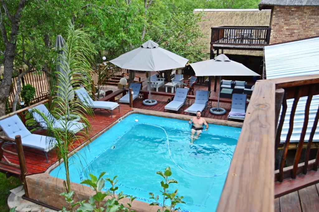 a man in a swimming pool on a deck at Pan African Lodge & Safari in Marloth Park