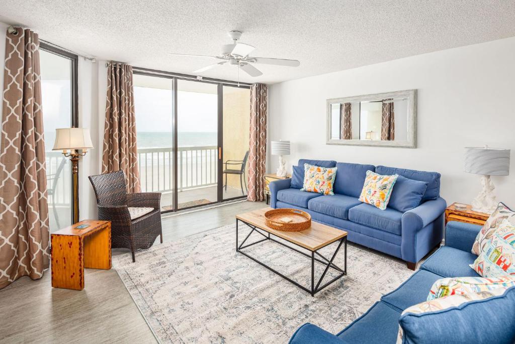 a living room with a blue couch and a table at 214 COV - Go Fly a Kite - Oceanfront Condo - 2 Pools in Folly Beach