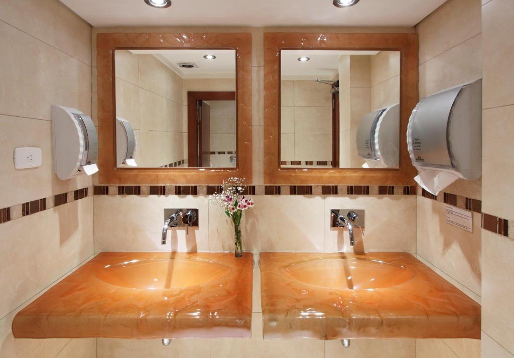 a bathroom with two sinks and two mirrors at Hotel Sheltown in Buenos Aires