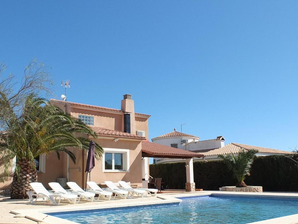 a villa with a swimming pool and lounge chairs at Villa Nerea with air conditioning & private swimming pool only 400m to the beach ideal for families in L'Ametlla de Mar