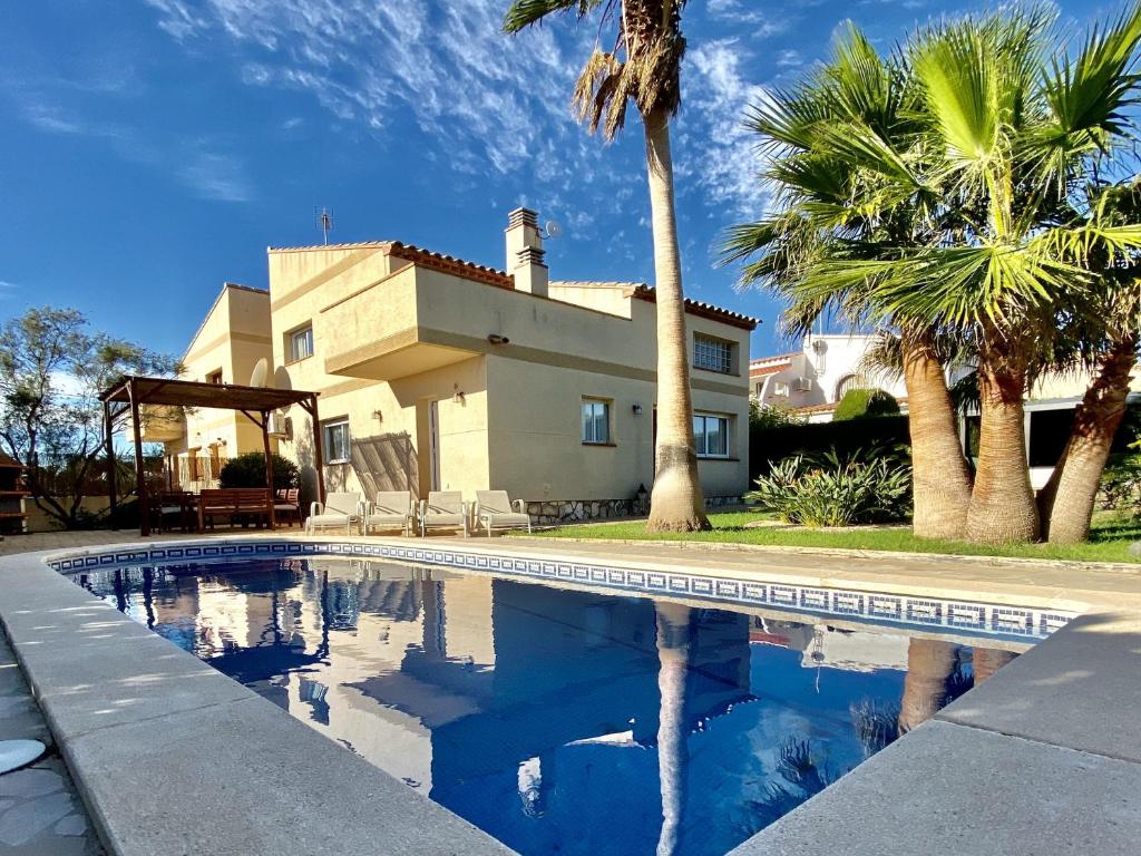 a swimming pool in front of a house with palm trees at Villa Martina 4 bedroom villa with air conditioning & private swimming pool ideal for families in L'Ametlla de Mar