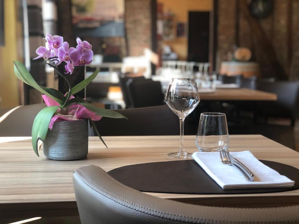 a table with a napkin and two glasses and a vase of flowers at L'auberge fleurie in Heilly