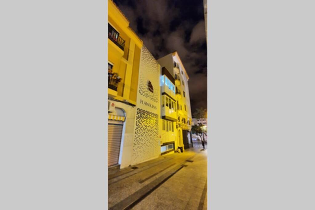 an empty street at night with a yellow building at Apartamento interior en el absoluto centro BA in Algeciras