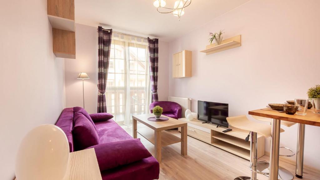 a living room with a purple couch and a tv at VacationClub - Osiedle Podgórze 1E Apartament 20 in Szklarska Poręba