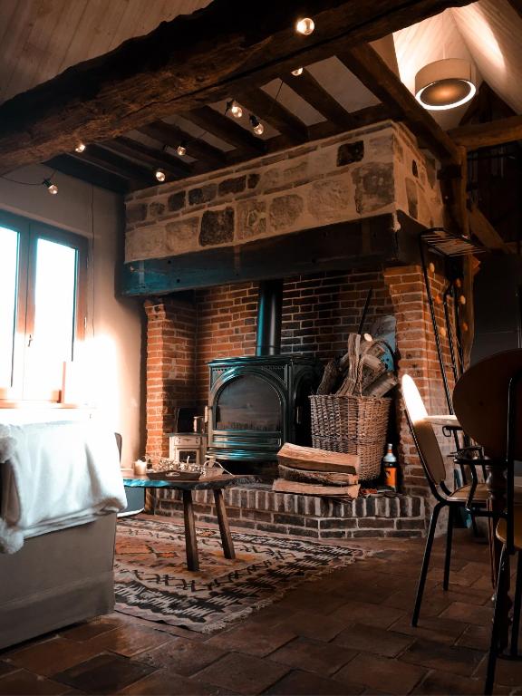 uma sala de estar com uma lareira de tijolos e uma mesa em Gîte au haras des arts em Saint-Aubin-de-Bonneval
