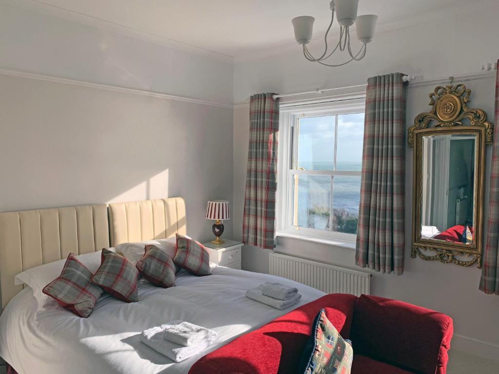 a bedroom with a bed with a mirror and a window at Ventnor Bay House in Ventnor