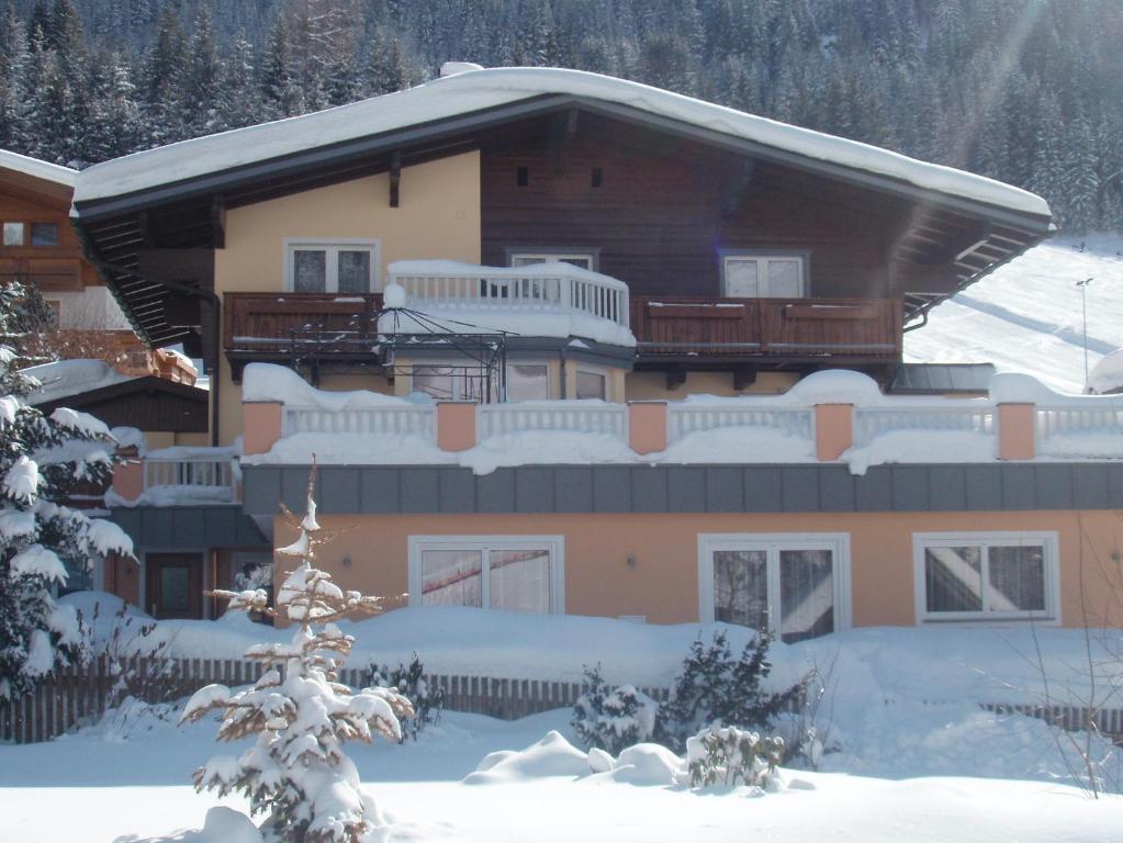 a house covered in snow in front of it at Landhaus Sonnrain in Saalbach Hinterglemm