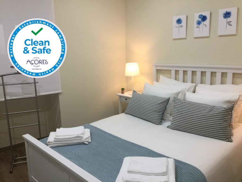 a bedroom with a bed with a sign that says clean and safe at Casa do Meio in Lagoa