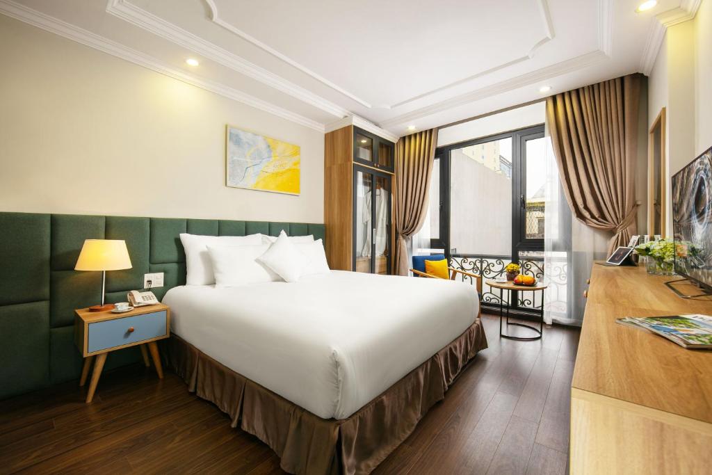 um quarto de hotel com uma cama grande e uma secretária em C'Bon Hotel Do Quang em Hanói