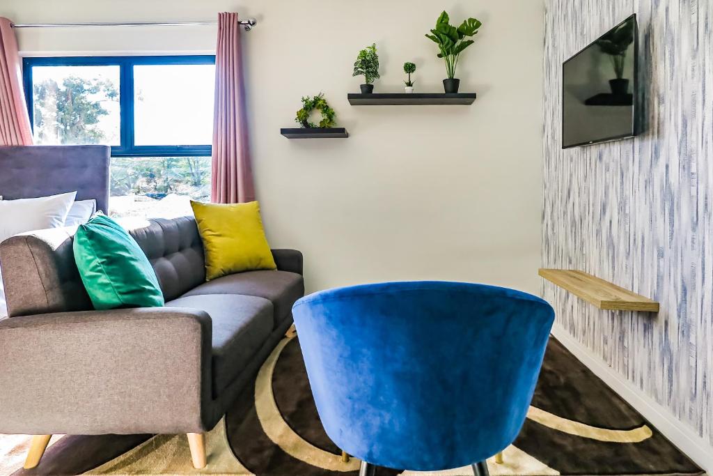 - un salon avec un canapé et un fauteuil bleu dans l'établissement Insaka's Greenlee Apartment - Greenlee Lifestyle Centre, Sandton, à Sandown