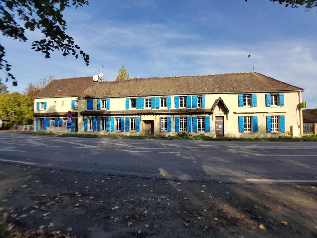 un grande edificio bianco con persiane blu su una strada di Chambres d'hôtes et Gîte Delia a Villeroy