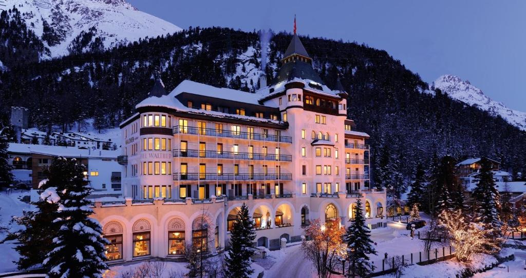 een groot gebouw in de sneeuw voor een berg bij Hotel Walther - Relais & Châteaux in Pontresina