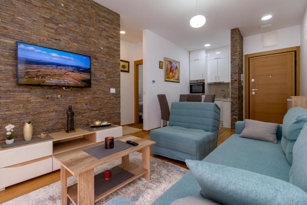 a living room with a couch and a tv on a brick wall at Nirvana 02 in Zlatibor