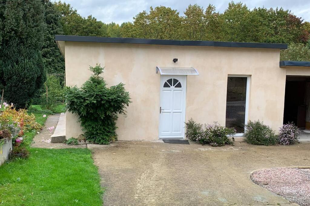 a small house with a white door in a yard at Studio indépendant Lisieux in Lisieux