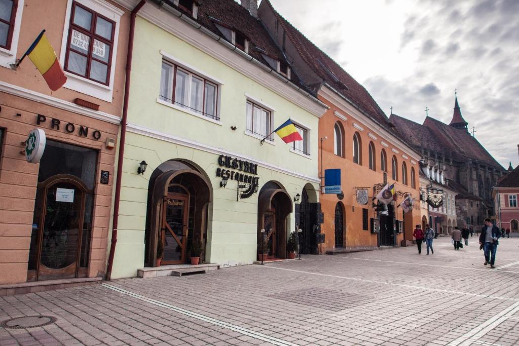 eine Straße mit Gebäuden und Menschen, die eine Straße hinuntergehen in der Unterkunft Residence Piata Sfatului in Braşov