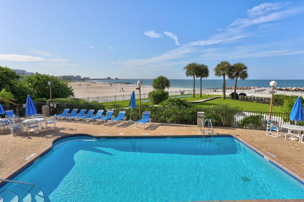 a swimming pool with chairs and a beach at Caprice Resort by Travel Resort Services in St. Pete Beach