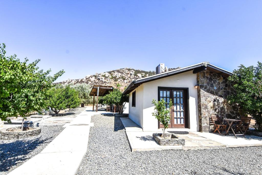 a small white building with trees and a mountain at Quinta Monasterio in Valle de Guadalupe