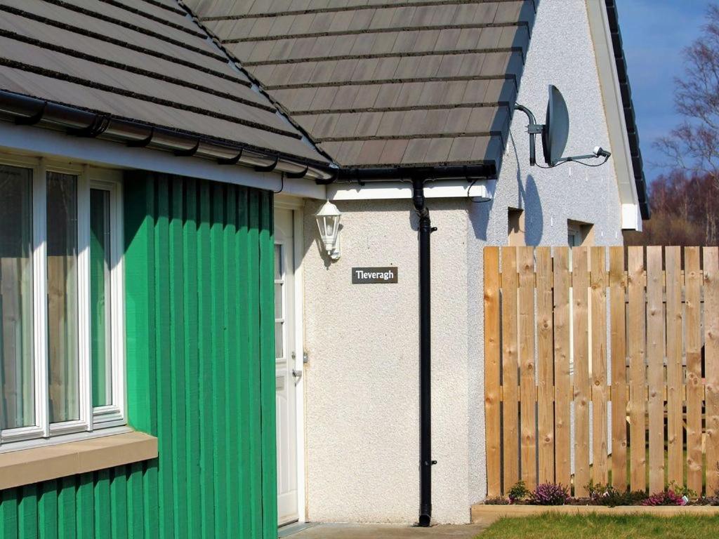 ein Haus mit einer grünen Tür und einem Zaun in der Unterkunft Tieveragh in Aviemore