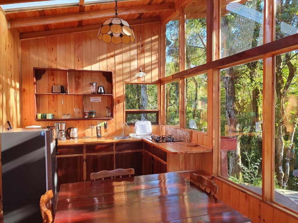 una cocina con mesa en una cabaña con ventanas en Finca Terra Viva, en Monteverde