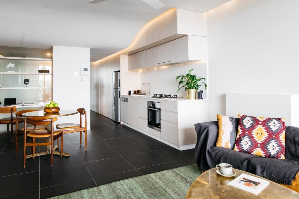 Nishi Apartments Eco Living by Ovolo في كانبرا: غرفة معيشة ومطبخ مع أريكة وطاولة