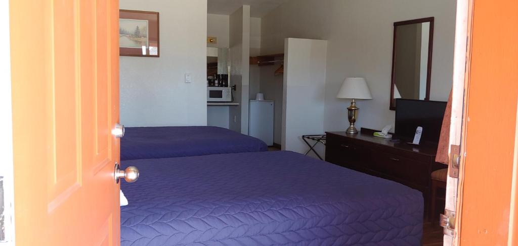 1 dormitorio con 2 camas y escritorio con TV en Western Inn Motel & RV Park, en Fairplay