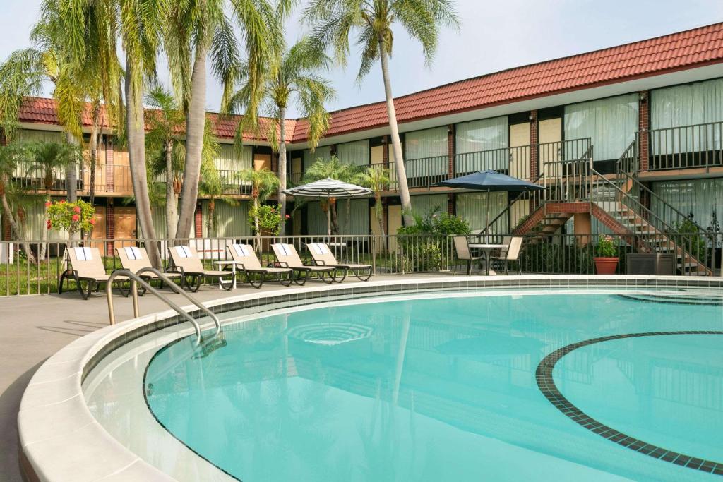 a swimming pool in front of a hotel with palm trees at Days Inn by Wyndham Clearwater/Central in Clearwater
