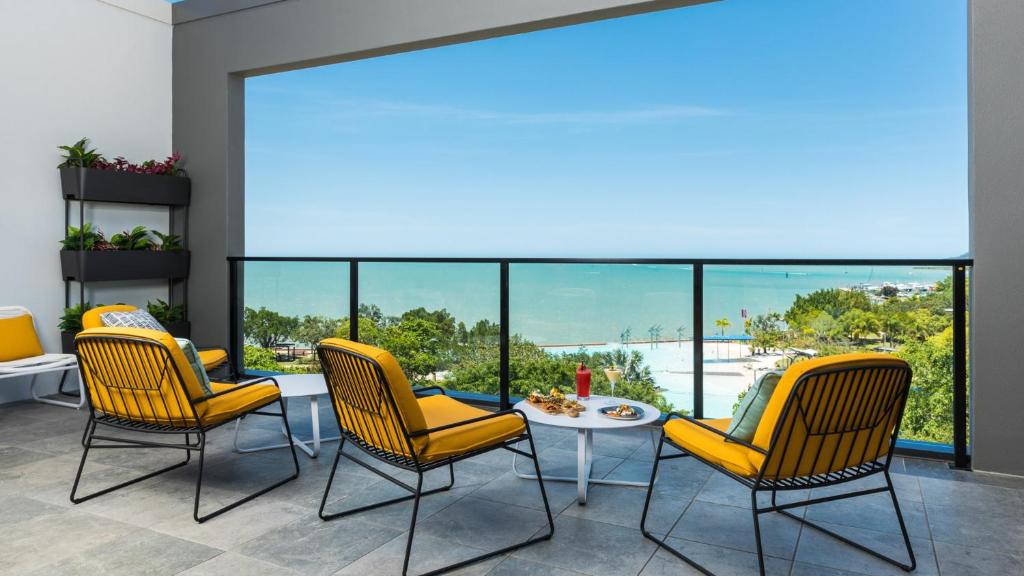 a waiting room with yellow chairs and a table and a large window at Oaks Cairns Hotel in Cairns