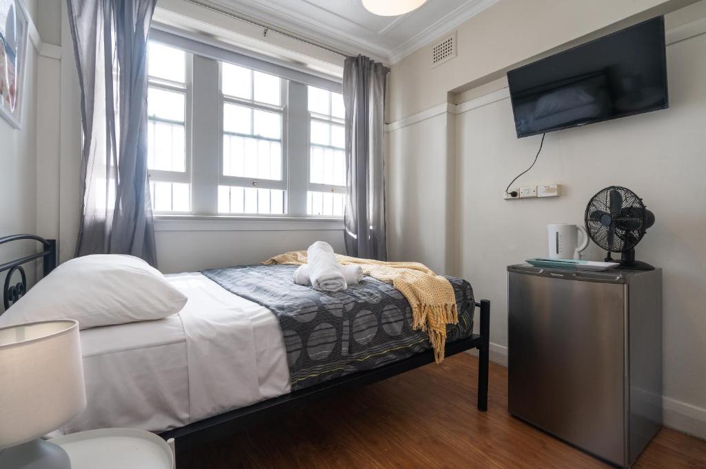 een slaapkamer met een bed, een tv en een raam bij Highfield Private Hotel in Sydney
