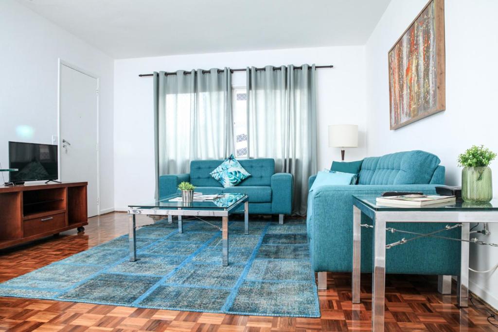 a living room with a blue couch and a table at Vila Olimpia Jade in São Paulo