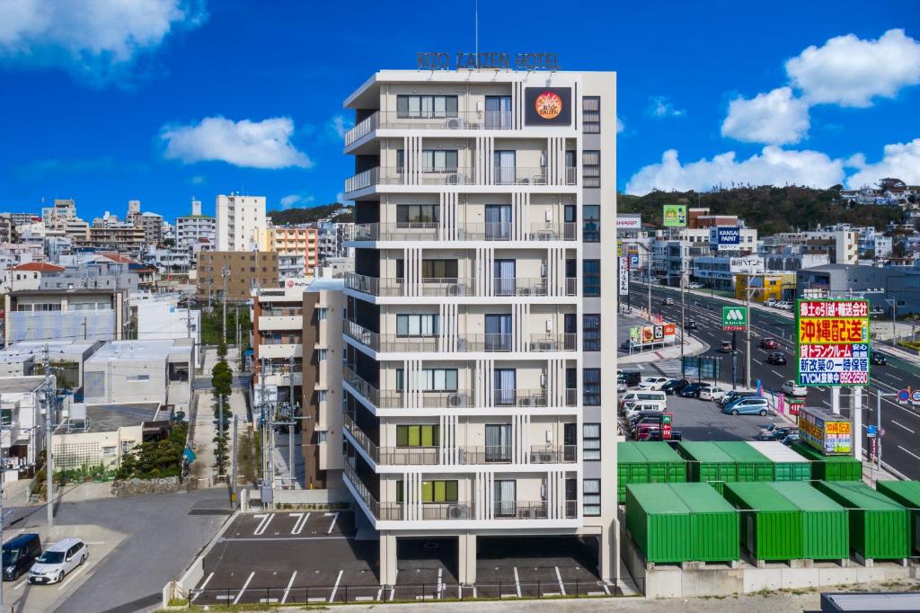 ein hohes weißes Gebäude in einer Stadt mit einer Straße in der Unterkunft リゾザイゼンホテル in Ginowan