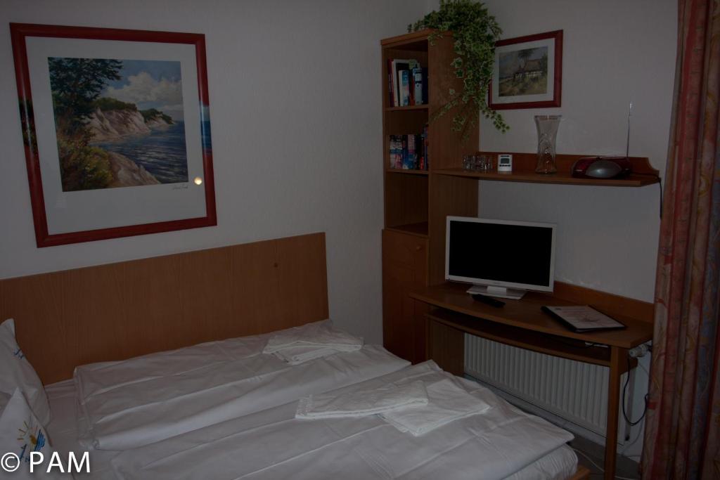 Schlafzimmer mit einem Bett und einem Schreibtisch mit einem Computermonitor in der Unterkunft Studio Meißner - Parkresidenz Dierhagen in Dierhagen