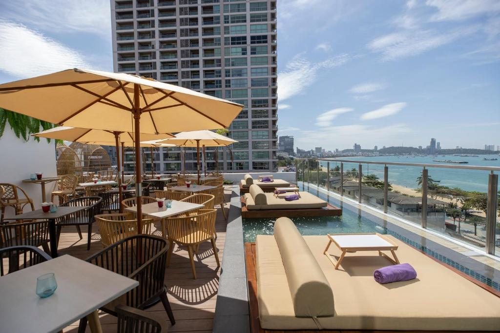 a restaurant with tables and chairs and a pool on a building at Pattaya Sea View Hotel - SHA Extra Plus in Pattaya Central