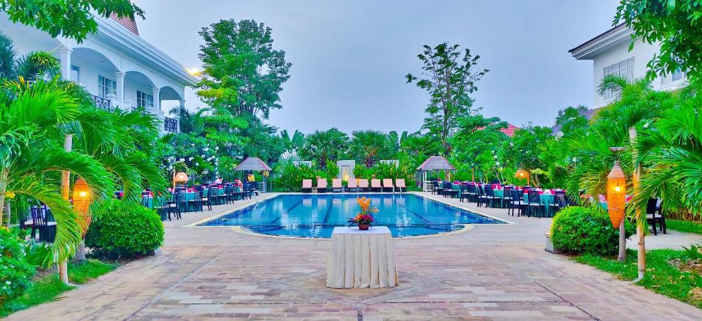 a pool at a resort with tables and chairs at Glorious Hotel & Spa in Kompong Thom