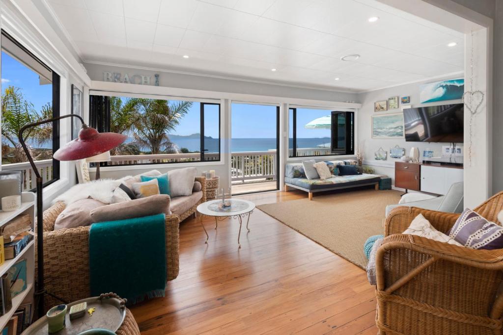 ein Wohnzimmer mit Blick auf das Meer in der Unterkunft Waipu Cove Palm Cottage - Waipu Cove Holiday Home in Waipu