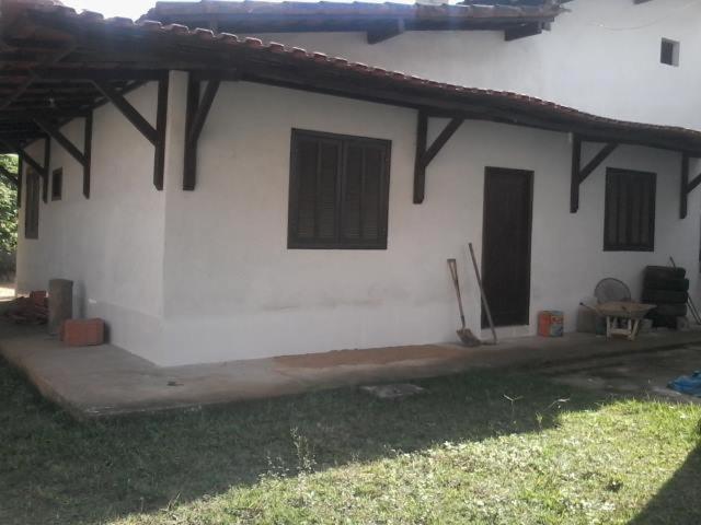biały budynek z czarnymi oknami i trawnikiem w obiekcie Pousada Sro Adilson w mieście Mangaratiba