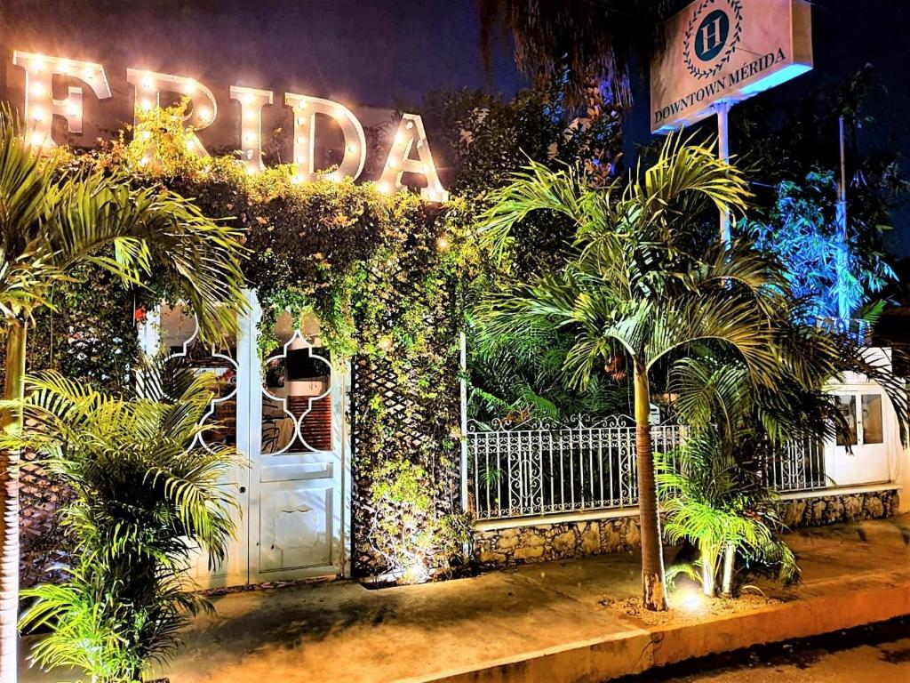 Hotel Downtown Merida في ميريدا: مبنى به بوابة بيضاء واشجار النخيل