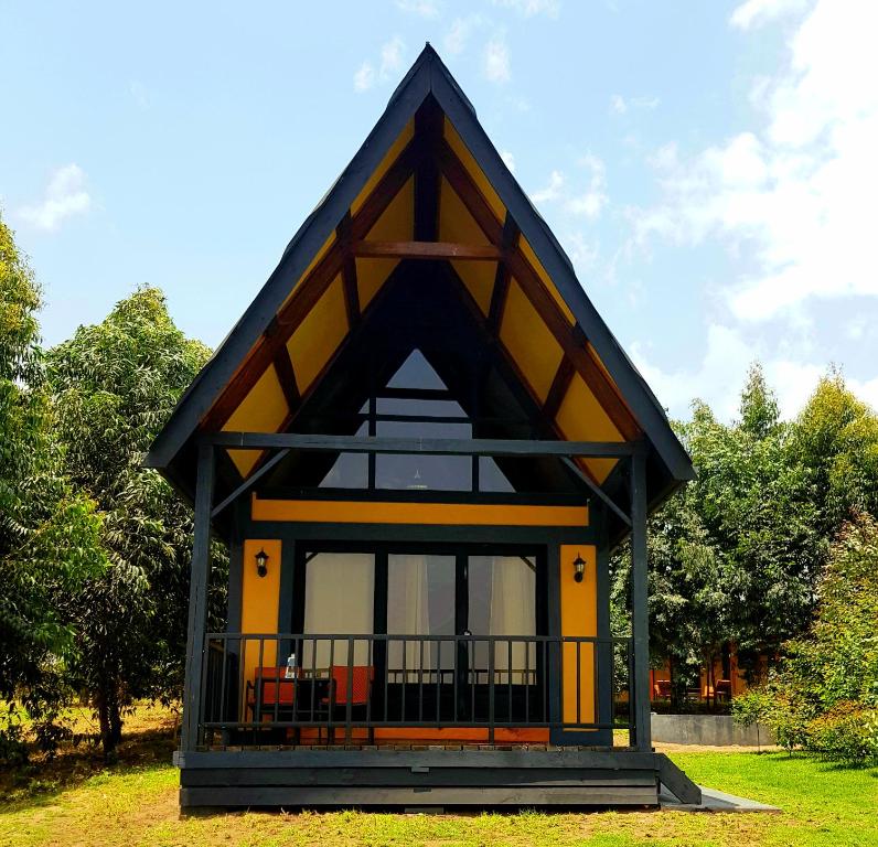 a small house with a black and yellow roof at Shamba lodge cabins in Arusha