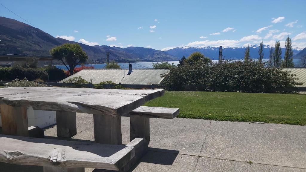 a wooden picnic table with a view of the mountains at 52sq Hawea Apartment, Lake and Mountain views!! in Wanaka