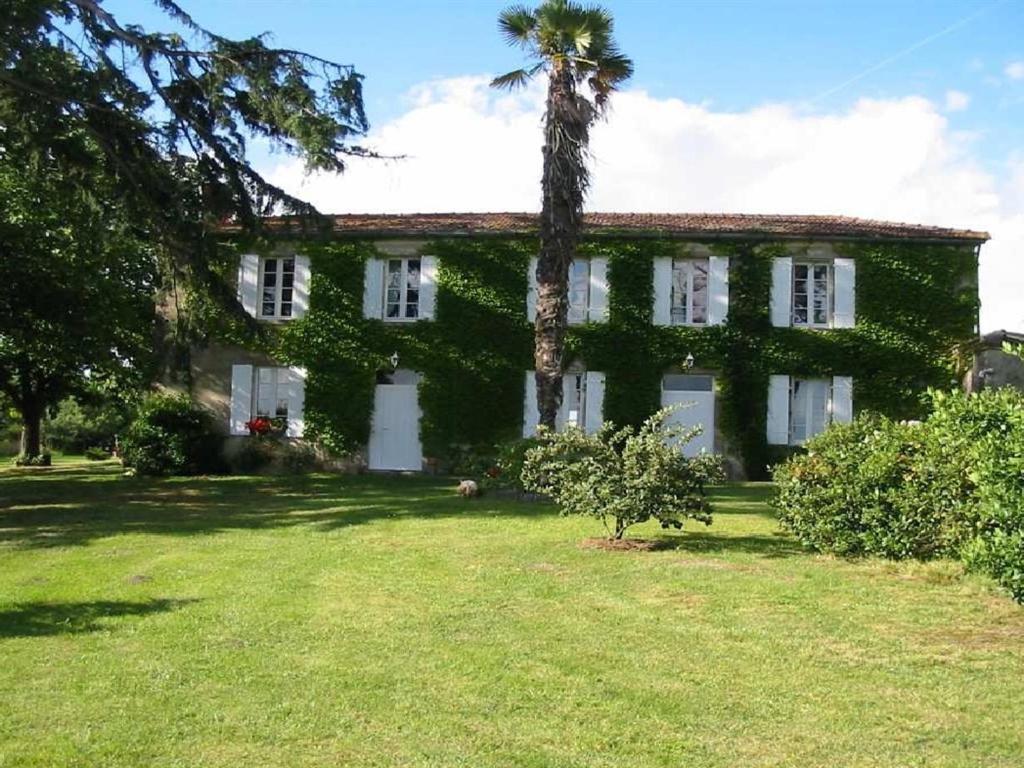 une maison ancienne avec un palmier dans la cour dans l'établissement Chambres d'Hôtes Domaine du Bouchon, à Gans