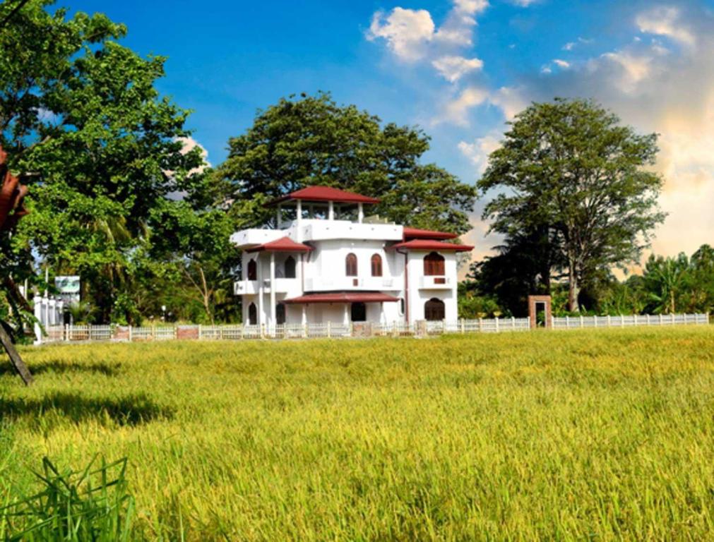 a building in a field with a green field at Green Heritage Holiday Resort in Mahiyangana