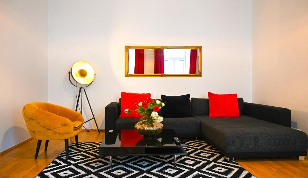 een woonkamer met een grijze bank en rode kussens bij Highlight Suite Universitaet Wien in Wenen