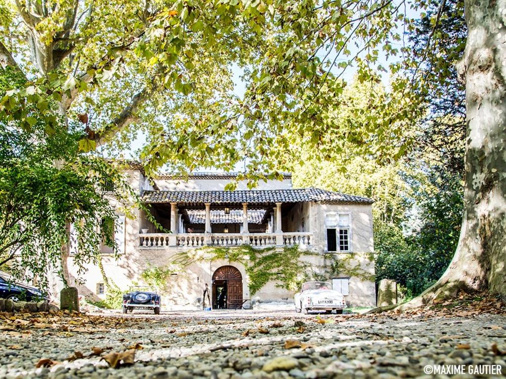 ein altes Haus mit zwei Autos davor geparkt in der Unterkunft Chambres d'Hôtes Château Beaupré in Saint-Laurent-des-Arbres