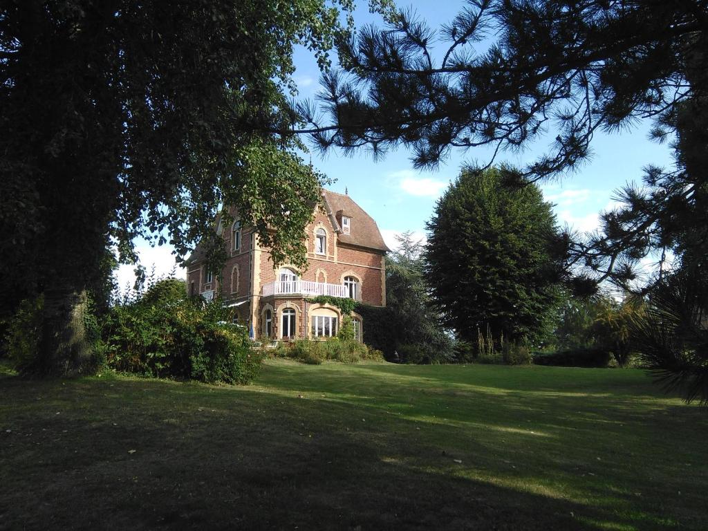 a large brick house in a field of grass at Le Sous-bois B&B in Moyenneville